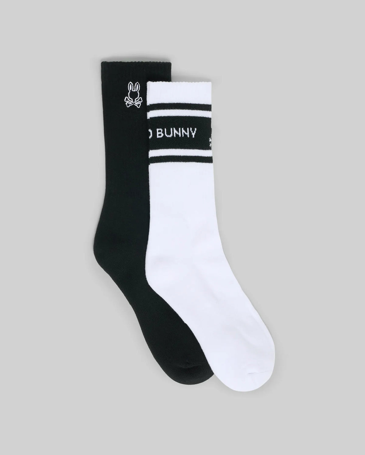 The Psycho Bunny MENS 2 PACK SPORT SOCK (MO2200037) features one black crew sock with a white bunny logo and one white crew sock with black stripes and "BUNNY" on the band—durable cotton for comfort and style.