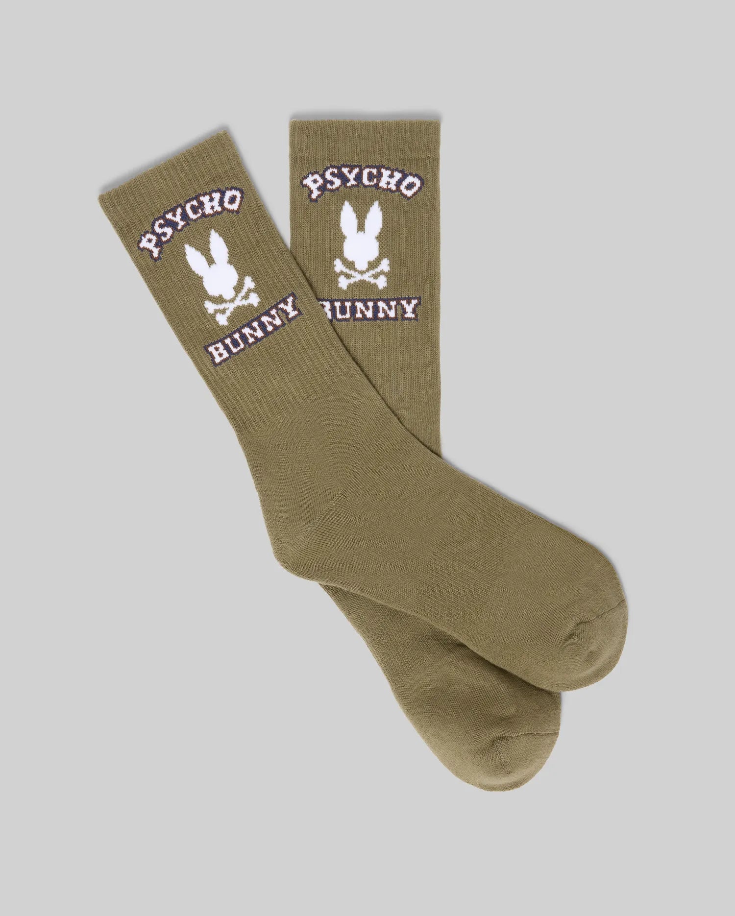 A pair of olive green Psycho Bunny MENS 2PK BUNNY SPORT SOCKS made from soft Pima cotton, featuring white "PSYCHO BUNNY" text above and below the bunny skull logo on the sides, shown on a light gray background.