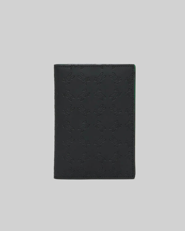Black Passport Holder with an all-over embossed Psycho Bunny skull logo pattern and subtle green accent on the interior edge, crafted from smooth, premium material.
