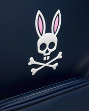 Navy CLASSIC BUNNY BACKPACK featuring a large, raised white and pink Psycho Bunny skull and crossbones logo, smooth texture, and visible zipper with contrast stitching. (2)