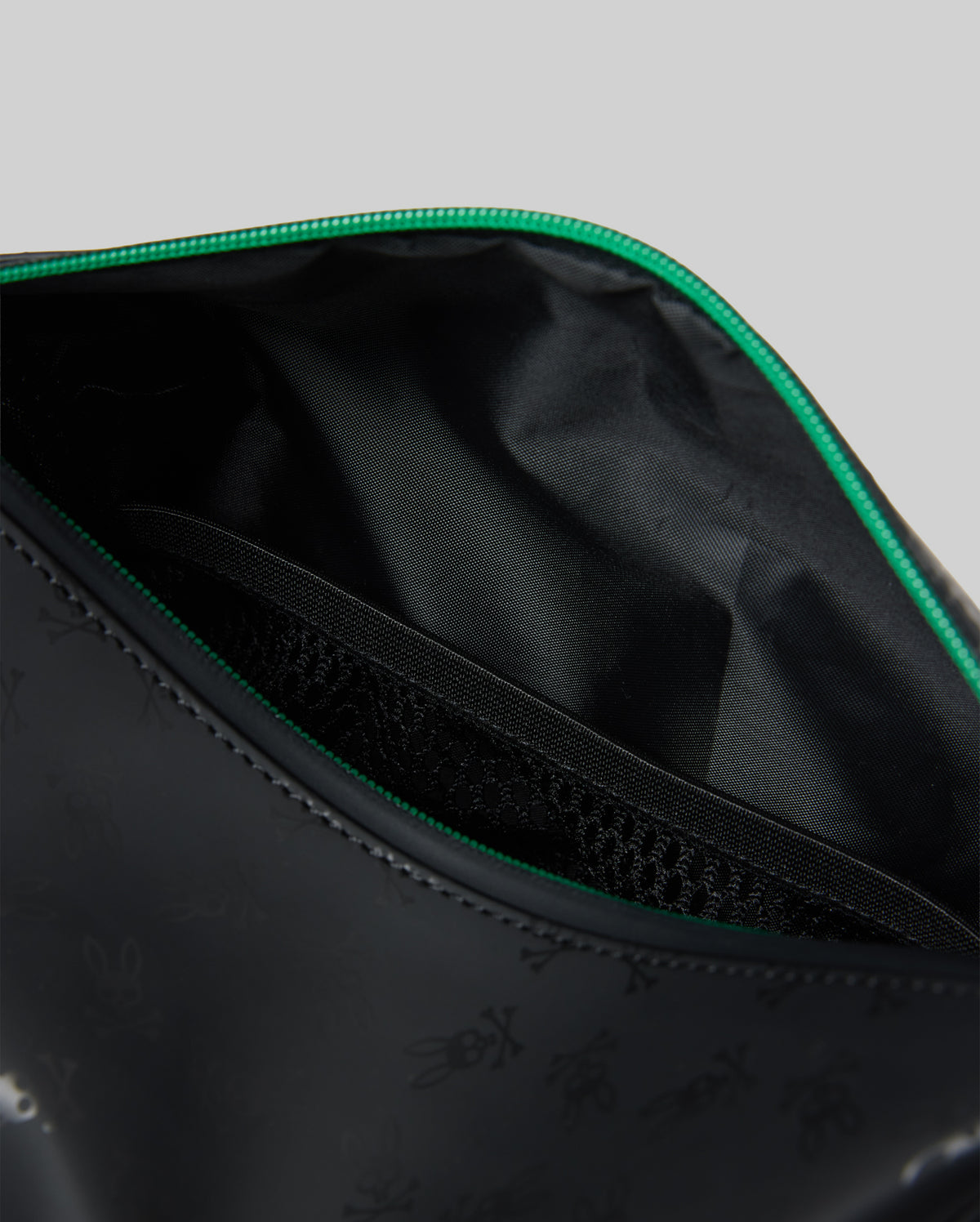 Mens All Over Bunny Toiletry Kit in black with a subtle all-over Psycho Bunny skull logo print, vibrant green zipper, smooth exterior, and an internal mesh pocket.