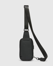 Black Crossbody Bag featuring a durable textured material, an adjustable strap with embossed Psycho Bunny logo text, a secure top zipper, and sleek black metal hardware. (4)