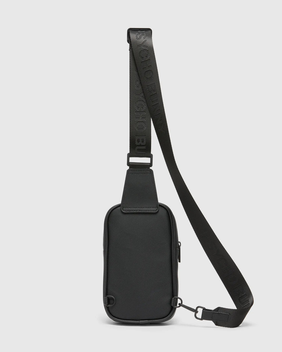 Black Crossbody Bag featuring a durable textured material, an adjustable strap with embossed Psycho Bunny logo text, a secure top zipper, and sleek black metal hardware. (4)
