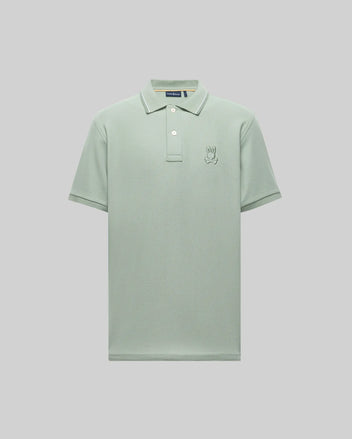 The Psycho Bunny Men's Fenley Pique Polo (MT0100009) is a light green, short-sleeve Pima cotton shirt with a collar, three buttons, and an embroidered Bunny logo on the left chest, shown on a plain gray background.