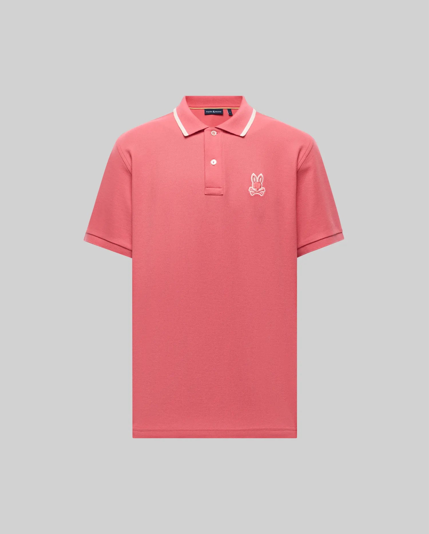 The Psycho Bunny MENS FENLEY PIQUE POLO (MT0100009) is a pink Pima cotton polo with a white collar trim, white buttons, and an embroidered Bunny logo on the left chest, shown against a light gray background.