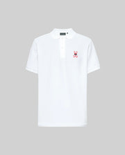 The Psycho Bunny MENS MISCHIEF BUNNY PIQUE POLO (MT0100025) is a white short-sleeve polo with a collar, three mother-of-pearl buttons, and a small pink bunny logo with crossbones on the left chest. Background is plain light gray.