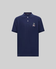 The Psycho Bunny MENS SONNY PIQUE POLO - MT0100094 is a navy blue Pima cotton short-sleeve polo with a collar, three buttons, and an embroidered palm tree and animal on the left chest, shown against a light gray background.