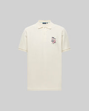 The Psycho Bunny MENS SONNY PIQUE POLO - MT0100094 is a cream Pima cotton short-sleeve polo with a collar, three buttons, and small chest embroidery, shown on a plain gray background.