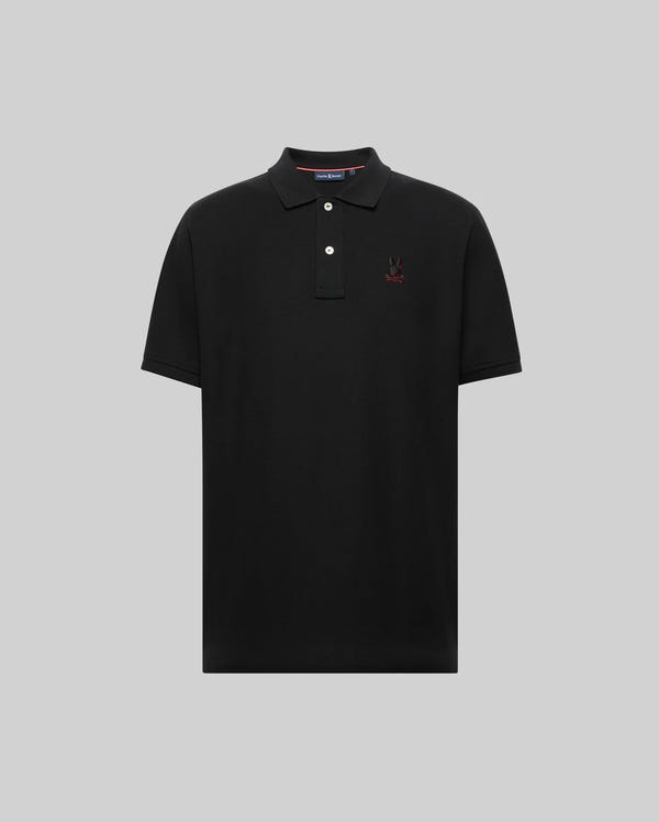 The Psycho Bunny MENS CASSIAN PIQUE POLO (MT0100098) is a black Pima cotton short-sleeve shirt with a collar, two white buttons, and an embroidered red and black logo on the left chest, shown on a gray background.