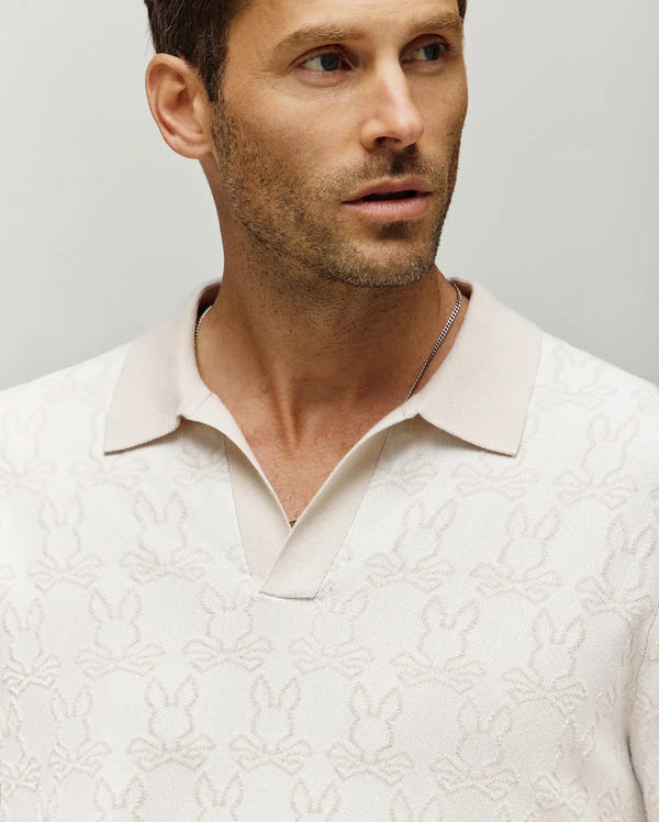 Mens Elden Johnny Collar Polo in cream, featuring a classic fit and an all-over subtle textured Psycho Bunny skull logo pattern with a contrasting beige Johnny collar.