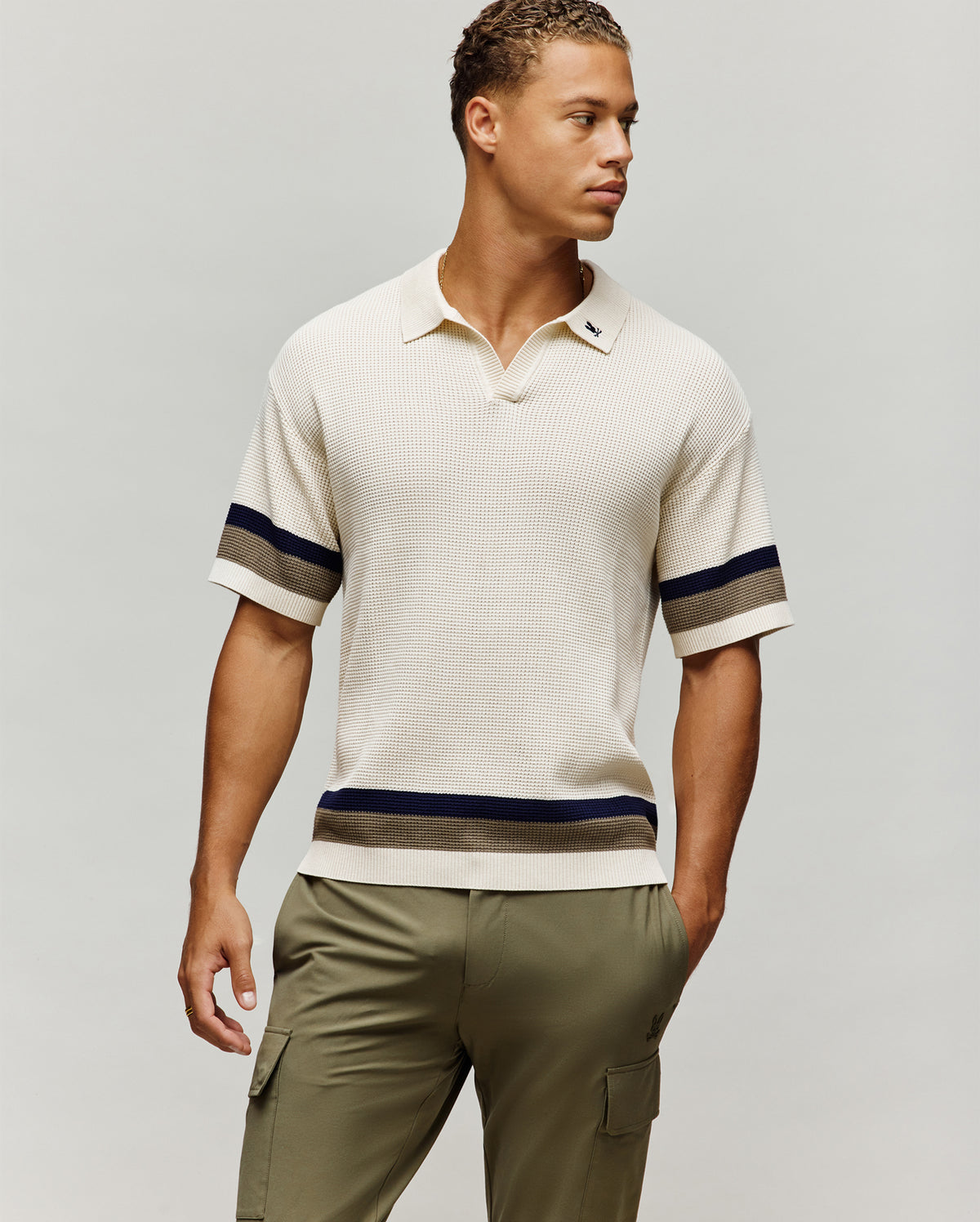 Mens Lochlan Oversized Johnny Collar Polo in cream waffle knit, featuring a small embroidered navy Psycho Bunny skull logo on the left chest and navy/olive stripes on the sleeves and hem.