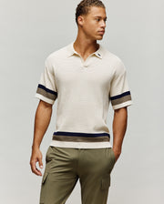 Mens Lochlan Oversized Johnny Collar Polo in cream waffle knit, featuring a small embroidered navy Psycho Bunny skull logo on the left chest and navy/olive stripes on the sleeves and hem.