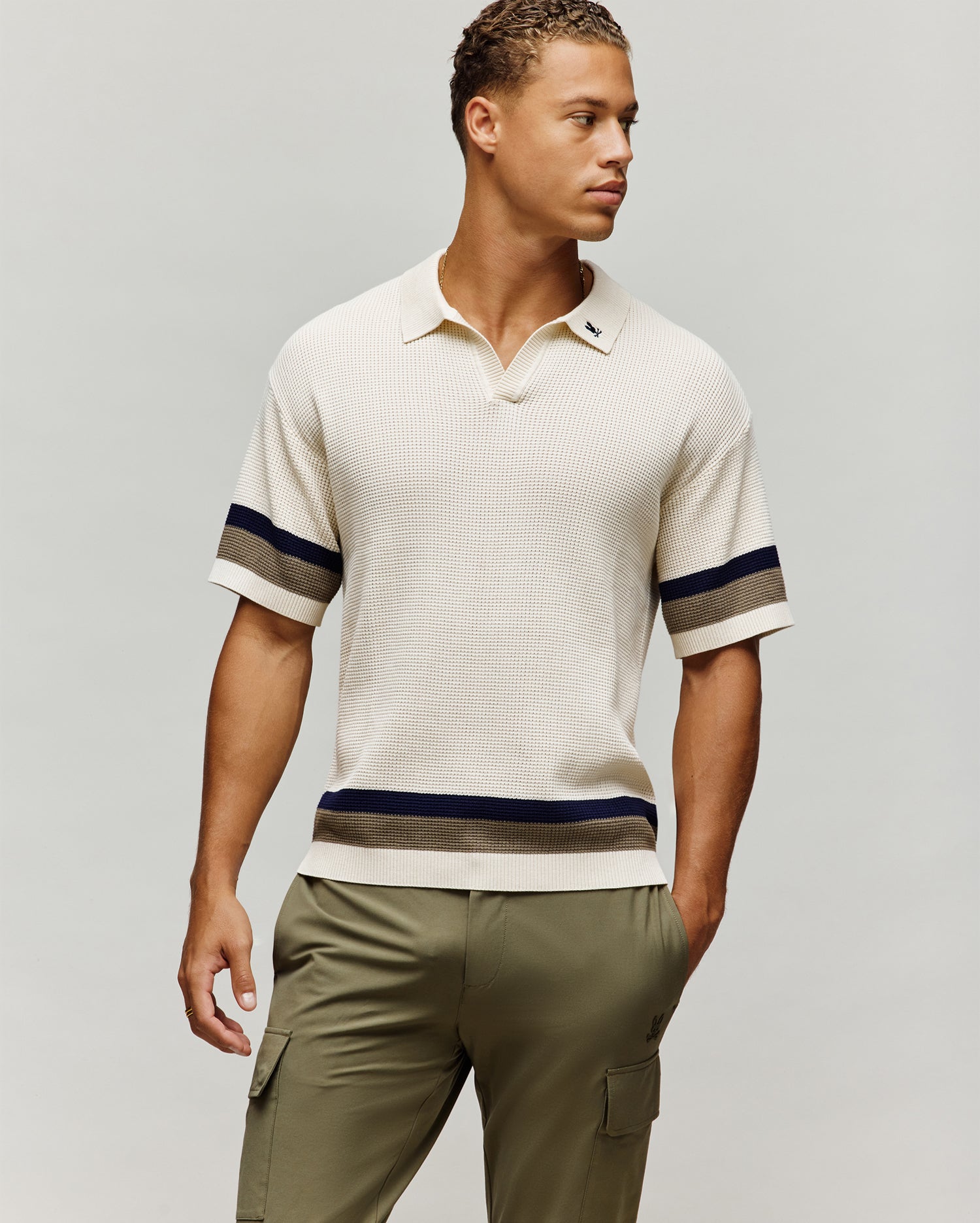Mens Lochlan Oversized Johnny Collar Polo in cream waffle knit, featuring a small embroidered navy Psycho Bunny skull logo on the left chest and navy/olive stripes on the sleeves and hem.