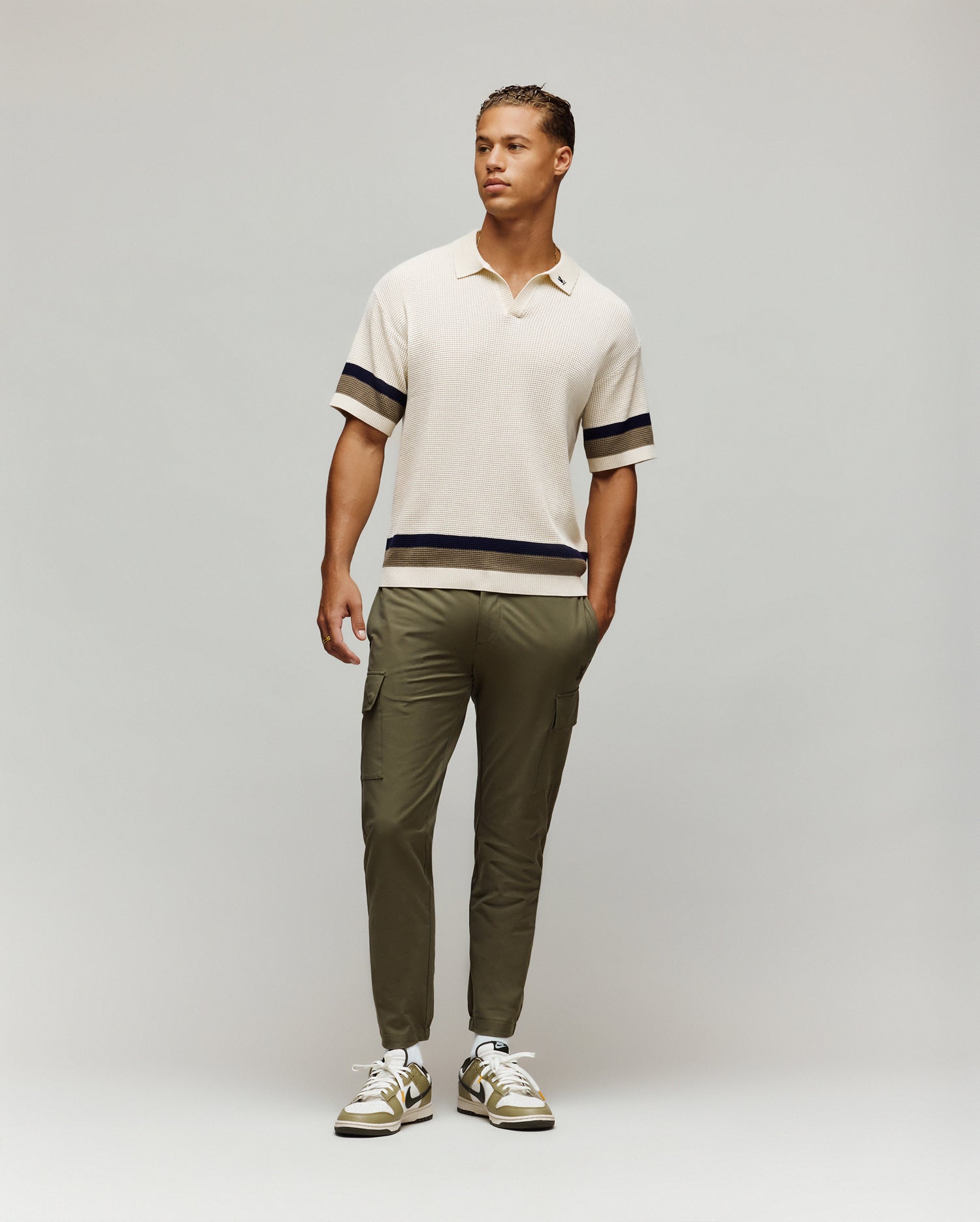 Mens Lochlan Oversized Johnny Collar Polo in cream waffle knit, featuring navy and olive stripes on sleeves and hem, with a small embroidered Psycho Bunny skull logo on the left chest.