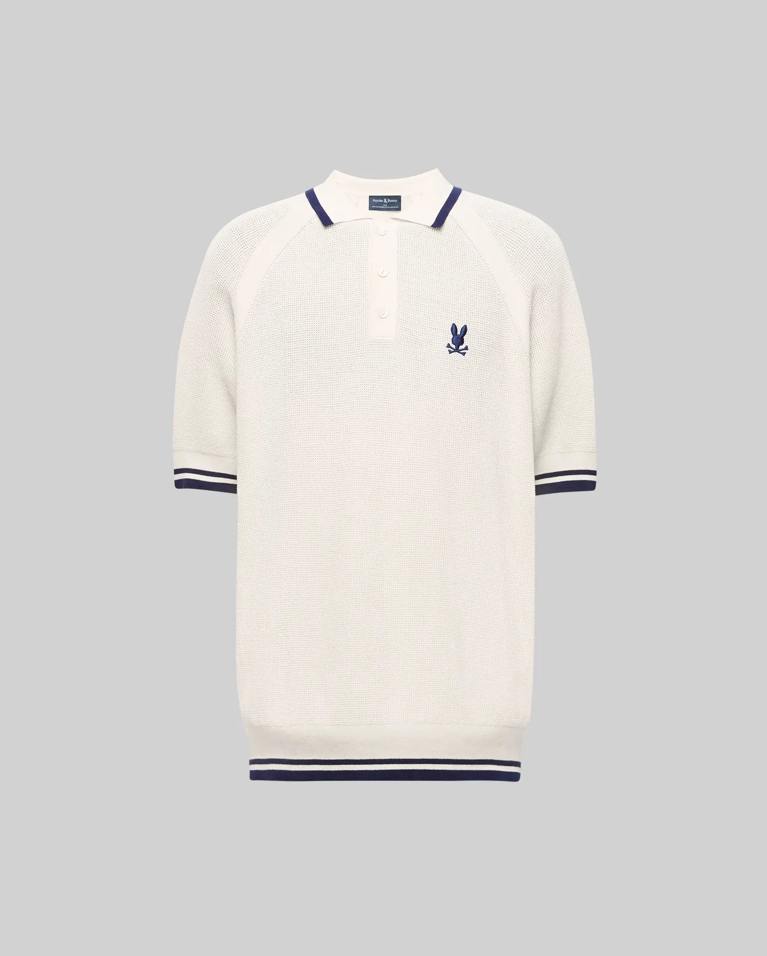 The Psycho Bunny MENS LAZARE KNIT POLO (MT0100165) is a short-sleeved, off-white textured polo with navy stripes on the collar, sleeves, and hem, a buttoned placket, and an embroidered bunny crest on the chest. Shown on a gray background.