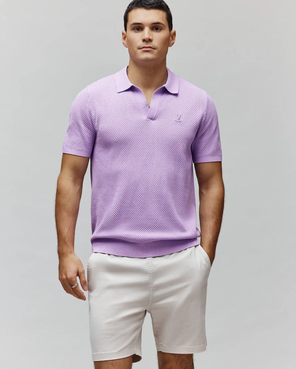 Mens Devon Knit Polo in lavender, featuring a textured knit fabric, classic fit, open collar, and a small embroidered Psycho Bunny skull logo on the left chest.