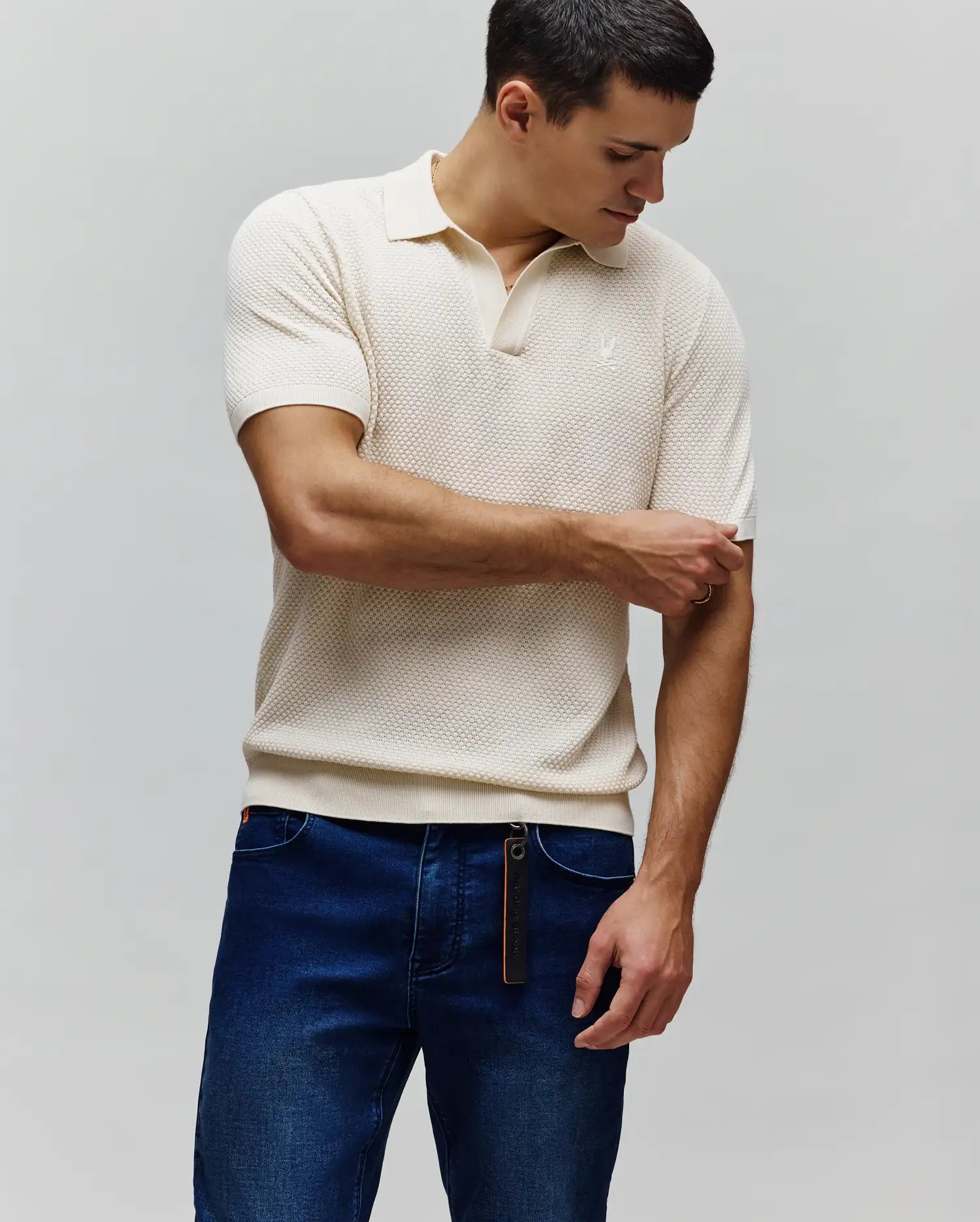 Mens Devon Knit Polo in cream, featuring a textured popcorn knit fabric, classic fit, ribbed cuffs and hem, and a small embroidered white Psycho Bunny skull logo on the left chest.
