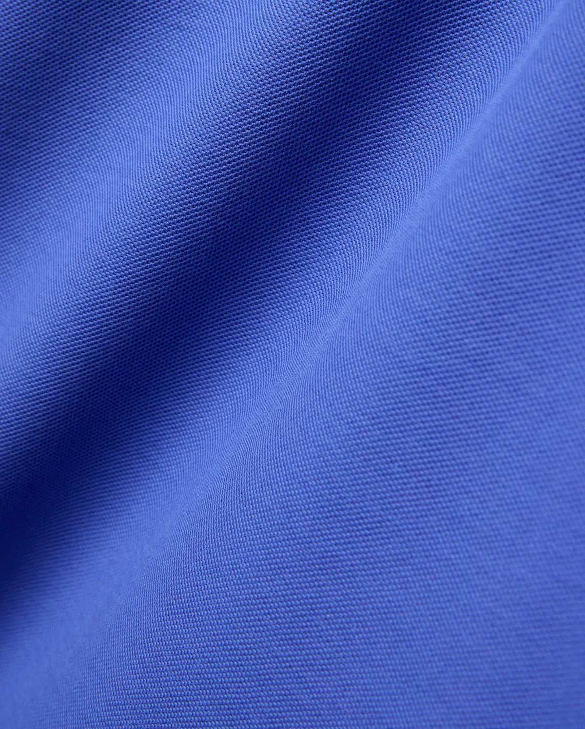 Close-up of the Mens Brad Pique Polo, featuring its vibrant royal blue color and classic textured pique knit fabric with soft, flowing folds. (5)