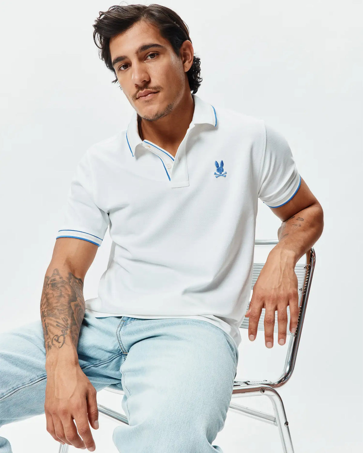 Mens Brad Pique Polo, white pique knit with blue trim on collar and sleeve cuffs, featuring an embroidered blue Psycho Bunny skull logo on the left chest, classic fit. (3)