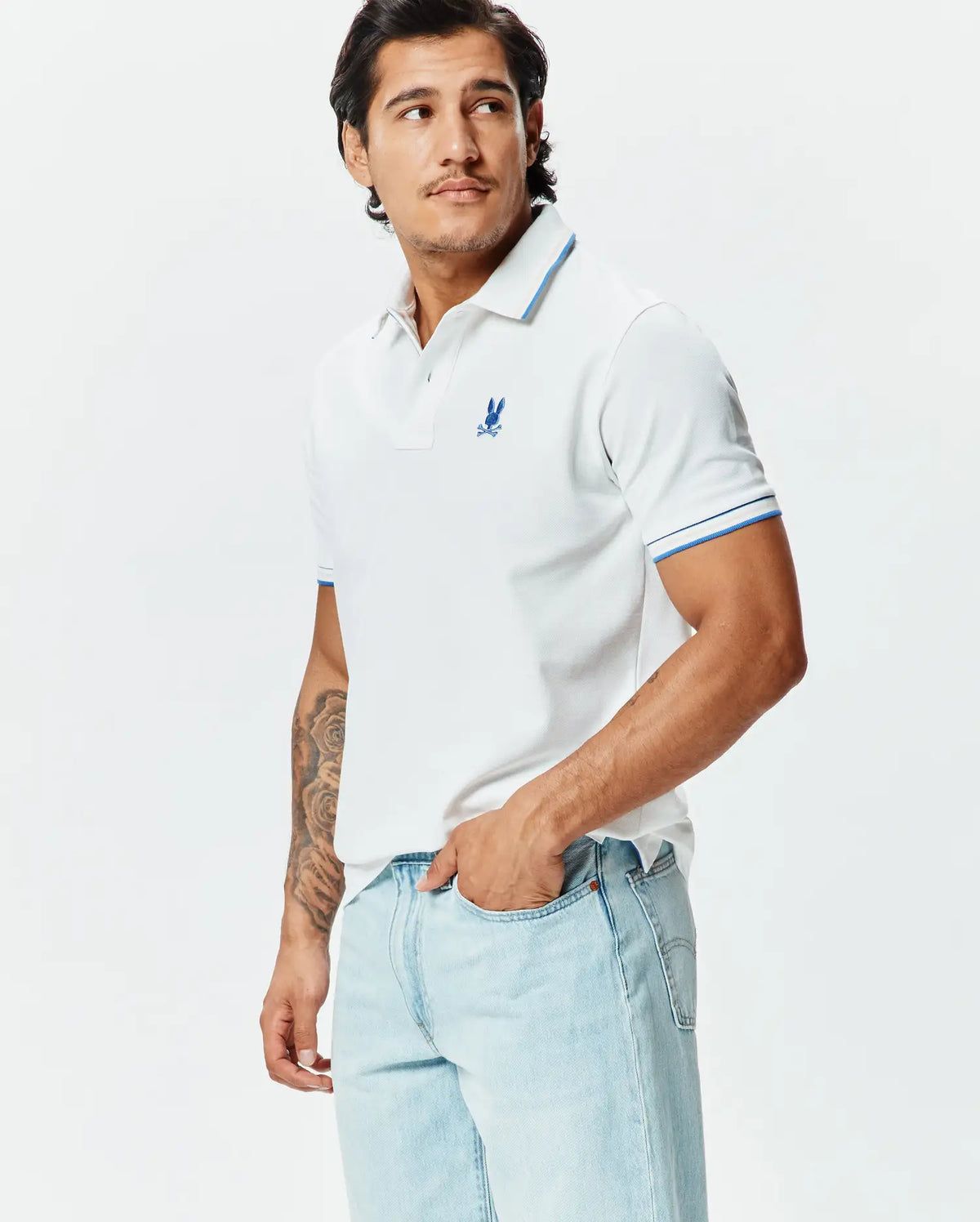 Mens Brad Pique Polo: White classic fit pique polo with blue tipped collar and cuffs, featuring a small embroidered blue Psycho Bunny skull logo on the left chest. (1)
