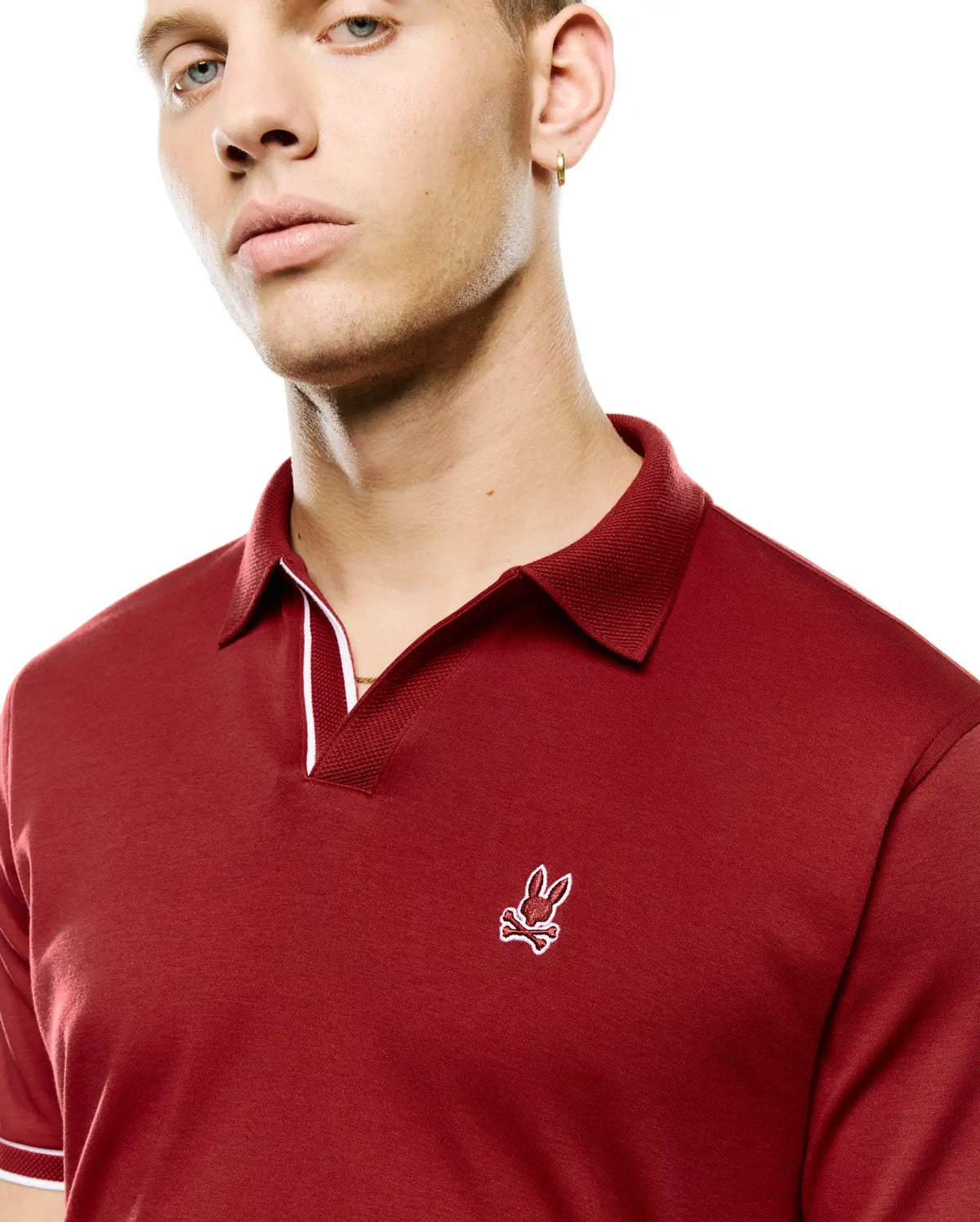 Men's Nasser Johnny Collar Polo in deep red, with a pique collar, jersey body, white tipping on collar and sleeve cuffs, and an embroidered white Psycho Bunny skull logo on the left chest. (2)