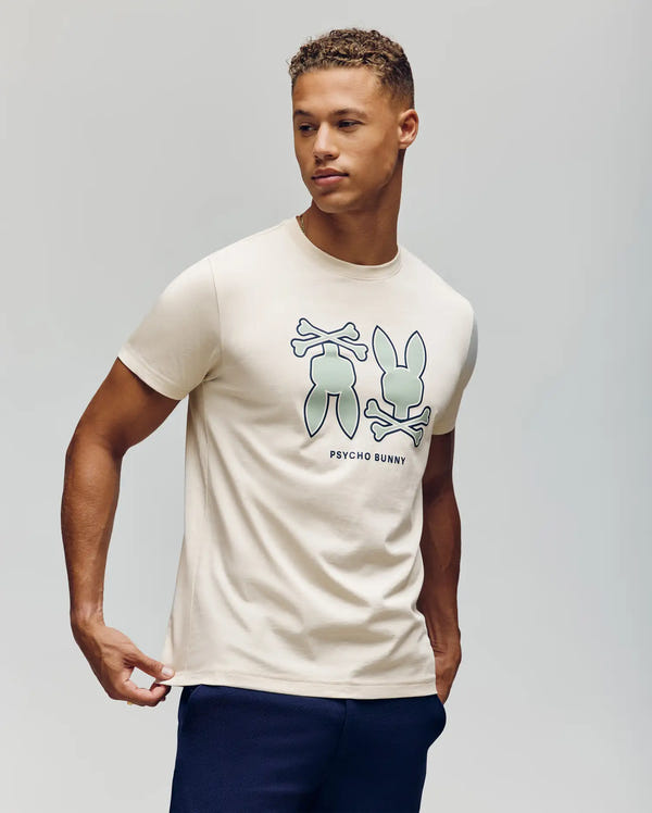 A man in the Psycho Bunny MENS DAWSON GRAPHIC TEE (MT0200053), a light Pima cotton shirt with two Bunny logo graphics and "PSYCHO BUNNY" text, looks to the side against a plain background.