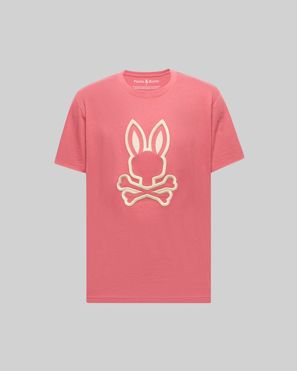 The Psycho Bunny MENS NICHOLAS EMBROIDERED TEE (MT0200054) is a pink T-shirt featuring a prominent white-outlined bunny head over crossed bones graphic on the front, shown against a plain gray background.