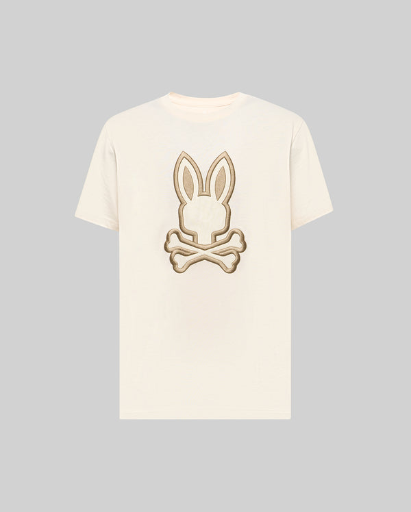 The Psycho Bunny MENS NICHOLAS EMBROIDERED TEE (MT0200054) features a cream base with a beige and brown embroidered bunny head and crossed bones motif centered on the chest.