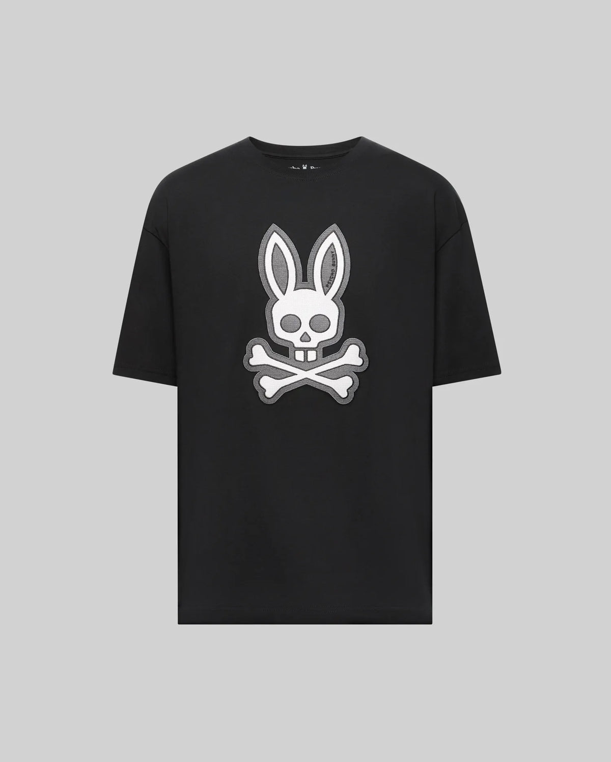 The Psycho Bunny MENS RYDER OVERSIZED TEE (MT0200062) is a black premium Pima cotton shirt with a bold white bunny head and long ears over a skull and crossbones graphic, displayed on a plain light gray background.