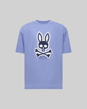 The Psycho Bunny MENS RYDER OVERSIZED TEE (MT0200062) is a light purple premium shirt with a bold front graphic of a skull with bunny ears above crossed bones, set on a plain gray background.