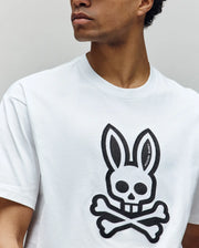 A person wears the Psycho Bunny MENS RYDER OVERSIZED TEE (MT0200062), a premium Pima cotton shirt with a large black skull and bunny ears graphic plus crossed bones on the front. The person's face is partially out of frame.