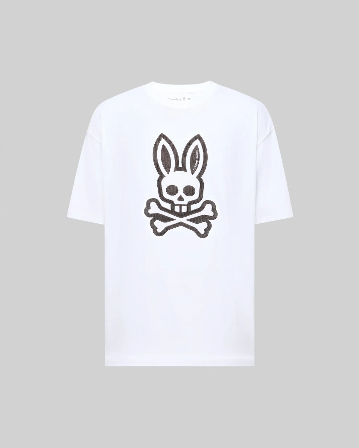 The Psycho Bunny MENS RYDER OVERSIZED TEE (MT0200062) features a bold black skull with bunny ears and crossed bones graphic on premium white Pima cotton, shown against a plain light gray background.