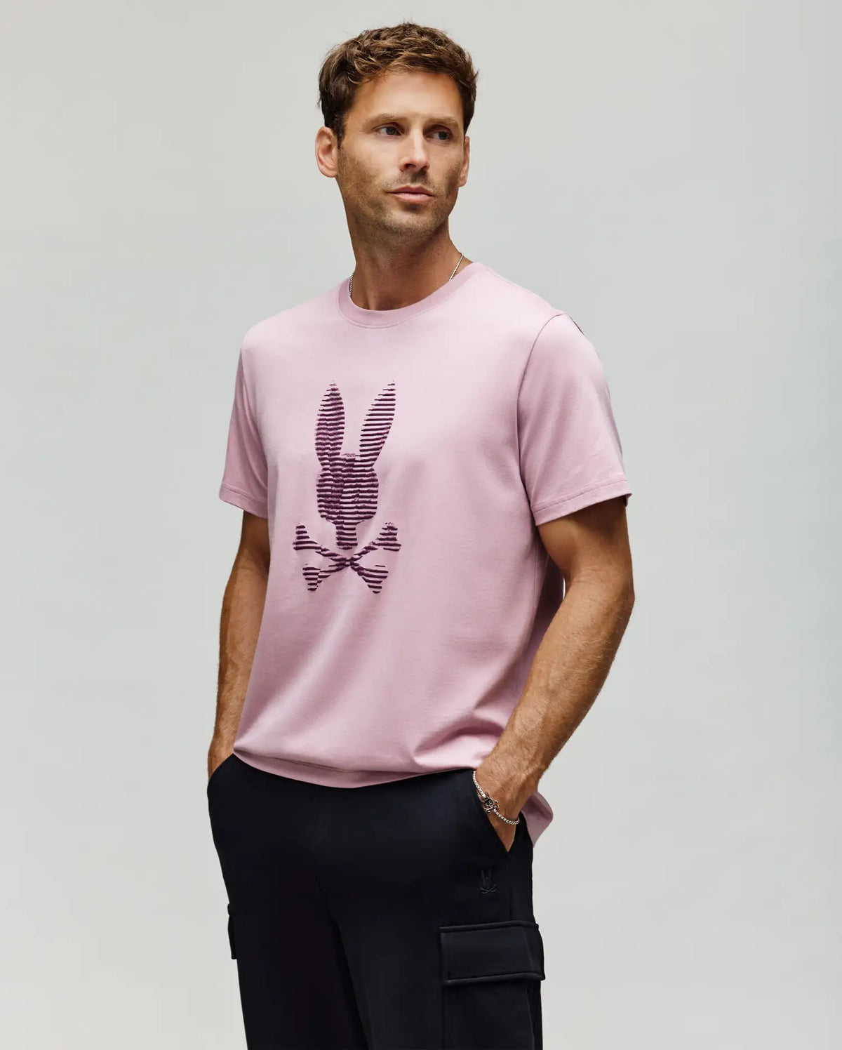 A man in a Psycho Bunny MENS GRANT BUNNY GRAPHIC TEE – MT0200081, crafted from soft Pima cotton.