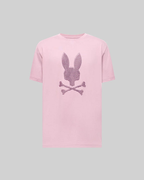 The Psycho Bunny MENS GRANT BUNNY GRAPHIC TEE - MT0200081 is a pink Pima cotton t-shirt featuring a rabbit head above crossed bones and dark stripes on the front, shown on a plain gray background.