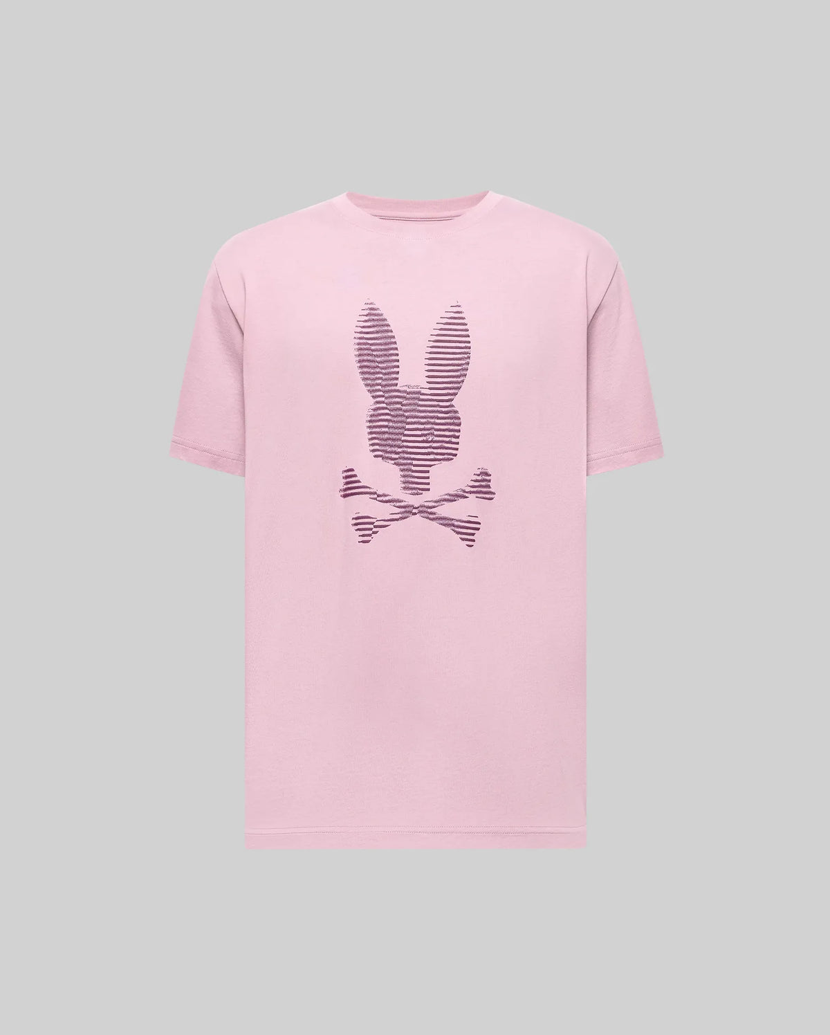 The Psycho Bunny MENS GRANT BUNNY GRAPHIC TEE - MT0200081 is a pink Pima cotton t-shirt featuring a rabbit head above crossed bones and dark stripes on the front, shown on a plain gray background.