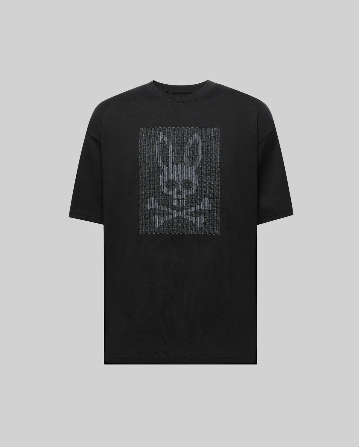 The Psycho Bunny MENS REECE OVERSIZED TEE (MT0200082) is a black relaxed fit shirt with a dark gray bunny skull and crossbones graphic on the chest, presented on a light gray background.