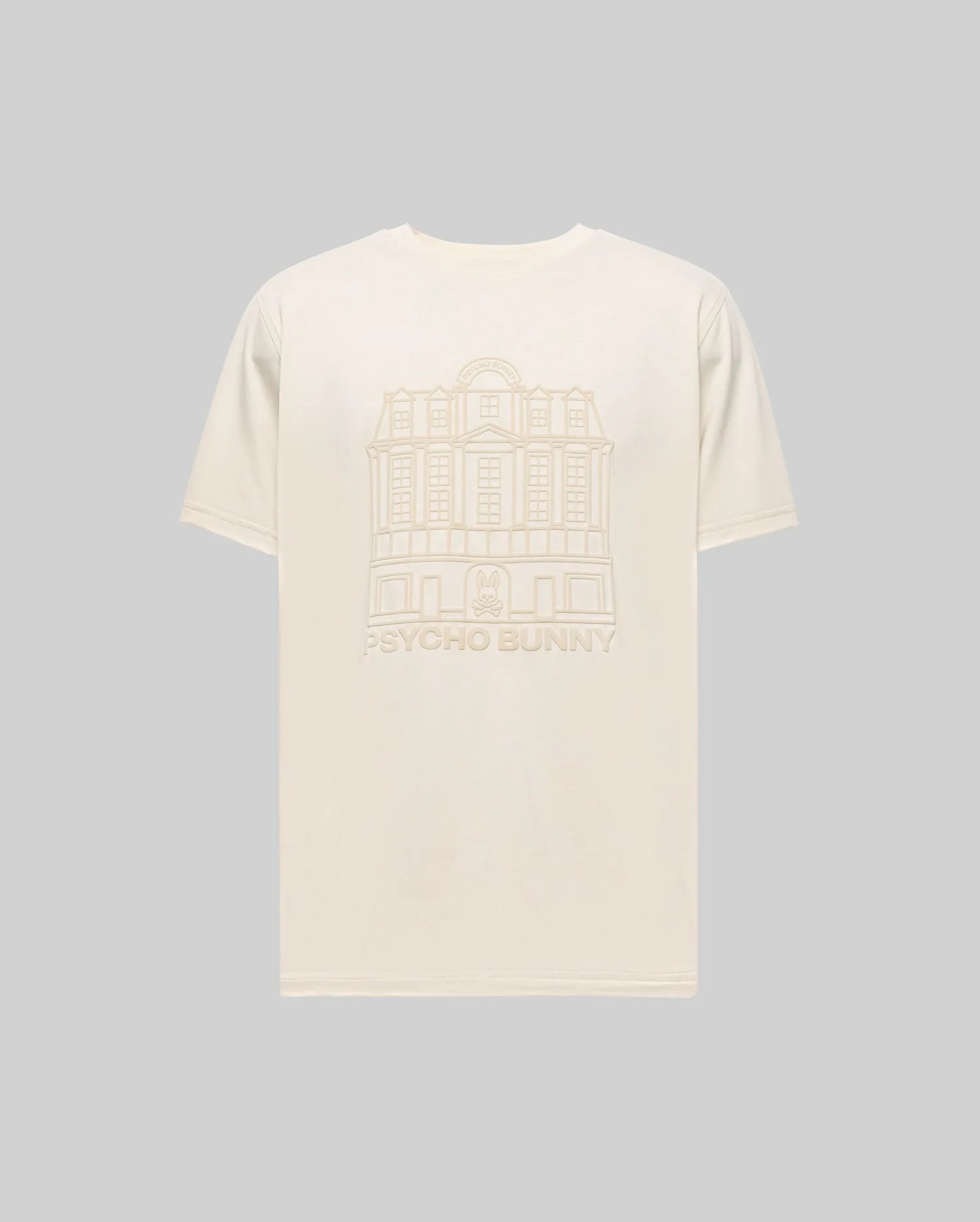 The Psycho Bunny MENS REDFORD GRAPHIC TEE (MT0200092) is a plain beige Pima cotton shirt with a subtle building line drawing and "PSYCHO BUNNY" text on the back, shown here against a light gray background.