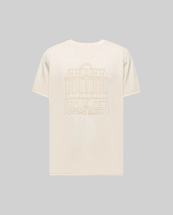 The Psycho Bunny MENS REDFORD GRAPHIC TEE (MT0200092) is a plain beige Pima cotton shirt with a subtle building line drawing and "PSYCHO BUNNY" text on the back, shown here against a light gray background.