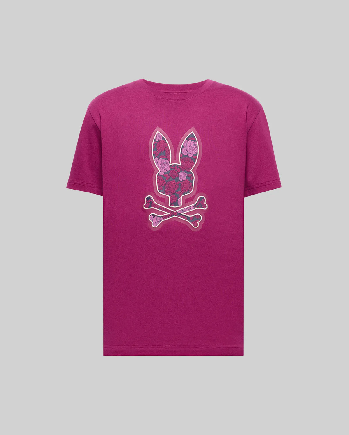 The Psycho Bunny MENS ROWEN BUNNY GRAPHIC TEE - MT0200101 is a magenta Pima cotton shirt with a bunny head, floral patterns, and crossed bones graphic on the chest, set against a plain light grey background.