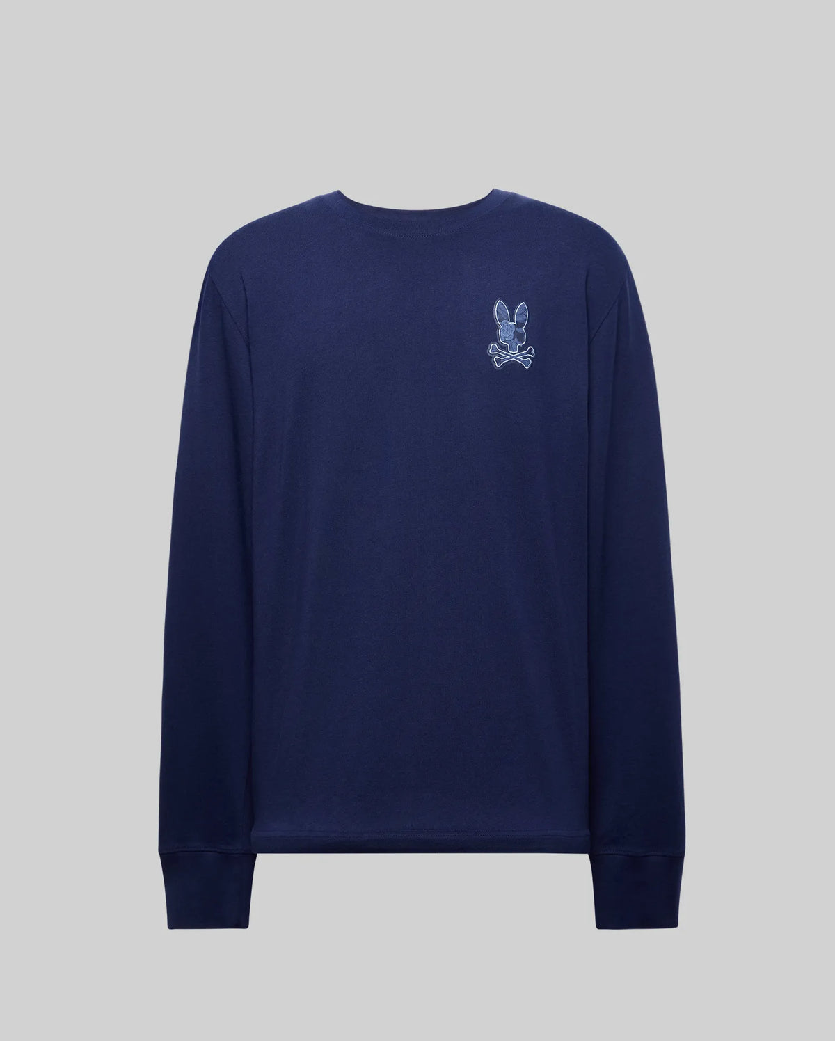 The Psycho Bunny MENS ROWEN GRAPHIC TEE (MT0200103) is a navy crewneck with ribbed cuffs, featuring a small white and light blue embroidered cartoon bunny and crossbones on the left chest, shown against a plain grey background.