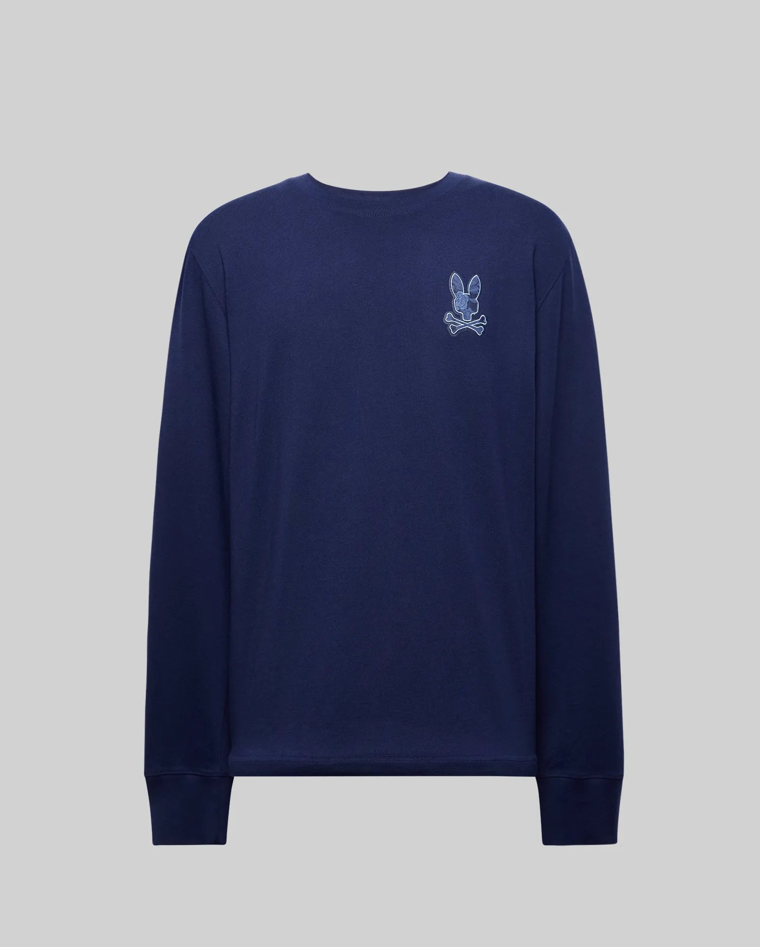 The Psycho Bunny MENS ROWEN GRAPHIC TEE (MT0200103) is a navy crewneck with ribbed cuffs, featuring a small white and light blue embroidered cartoon bunny and crossbones on the left chest, shown against a plain grey background.