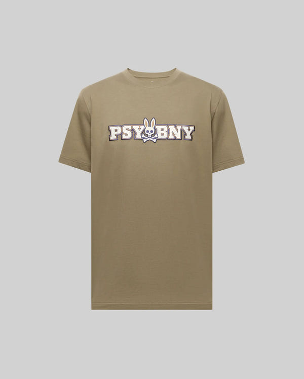 The Psycho Bunny MENS WADE GRAPHIC TEE (MT0200105) is a regular fit khaki short-sleeve shirt, featuring a white and black "PSYBNY" and cartoon bunny face with crossbones on the chest, made from 100% cotton. Displayed on a light grey background.