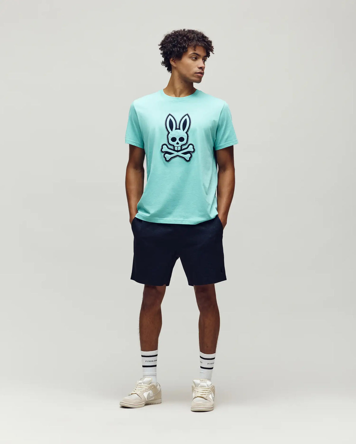 Mens Gage Graphic Tee in aqua jersey knit, featuring a large, bold black and white Psycho Bunny skull logo on the center chest, classic fit.
