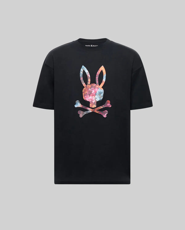 The Psycho Bunny MENS NOVAN GRAPHIC TEE (MT0200177) is a black regular-fit shirt with a large bunny skull and crossbones graphic, featuring a colorful marble pattern, shown on a plain gray background.