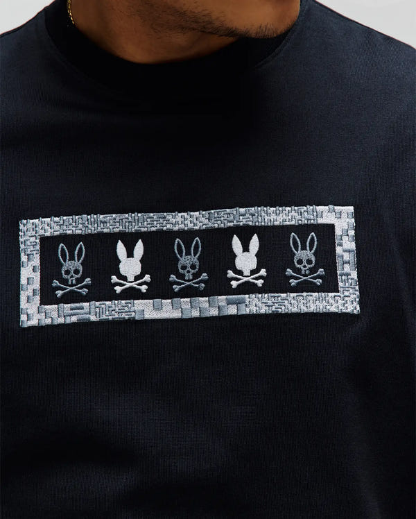 Black Mens Olivier Oversized Tee, jersey knit, with a large central embroidered grey and white rectangular patch featuring five Psycho Bunny skull logos, one solid white.