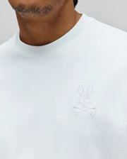 Mens Oscar Oversized Tee, white jersey knit with a relaxed fit, featuring a small, tonal white embroidered Psycho Bunny skull and crossbones logo on the left chest.