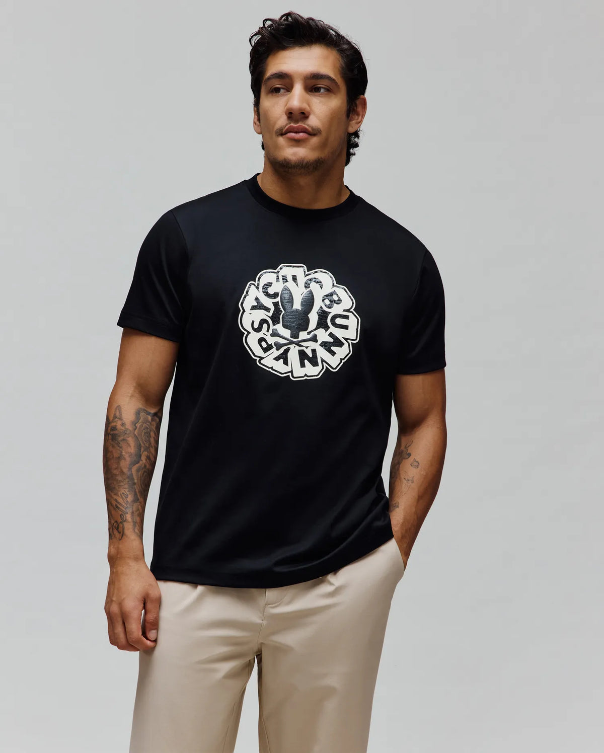 Mens Toby Graphic Tee, a black classic fit jersey t-shirt featuring a large distressed white circular Psycho Bunny skull logo and text graphic centered on the chest.