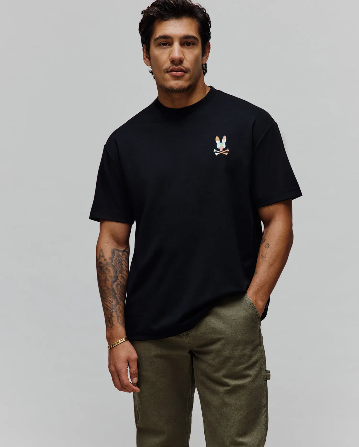 Black Mens Ara Oversized Tee, crafted from soft jersey fabric, featuring a relaxed fit and a small, vibrant, multicolored embroidered Psycho Bunny skull logo on the left chest.