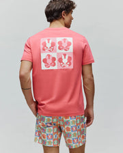 Mens Aiden Back Graphic Tee in coral pink jersey knit, featuring a classic fit and a large back graphic with a checkerboard of white and light pink squares, each containing a dark pink Psycho Bunny skull logo within a flower shape.