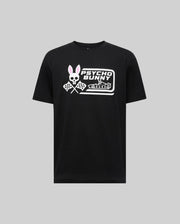 The Psycho Bunny MENS RACING GRAPHIC TEE (MT0200243) is a black Pima cotton t-shirt featuring a bold white skull bunny logo with pink ears, crossed checkered flags, and "Psycho Bunny" text across the chest.